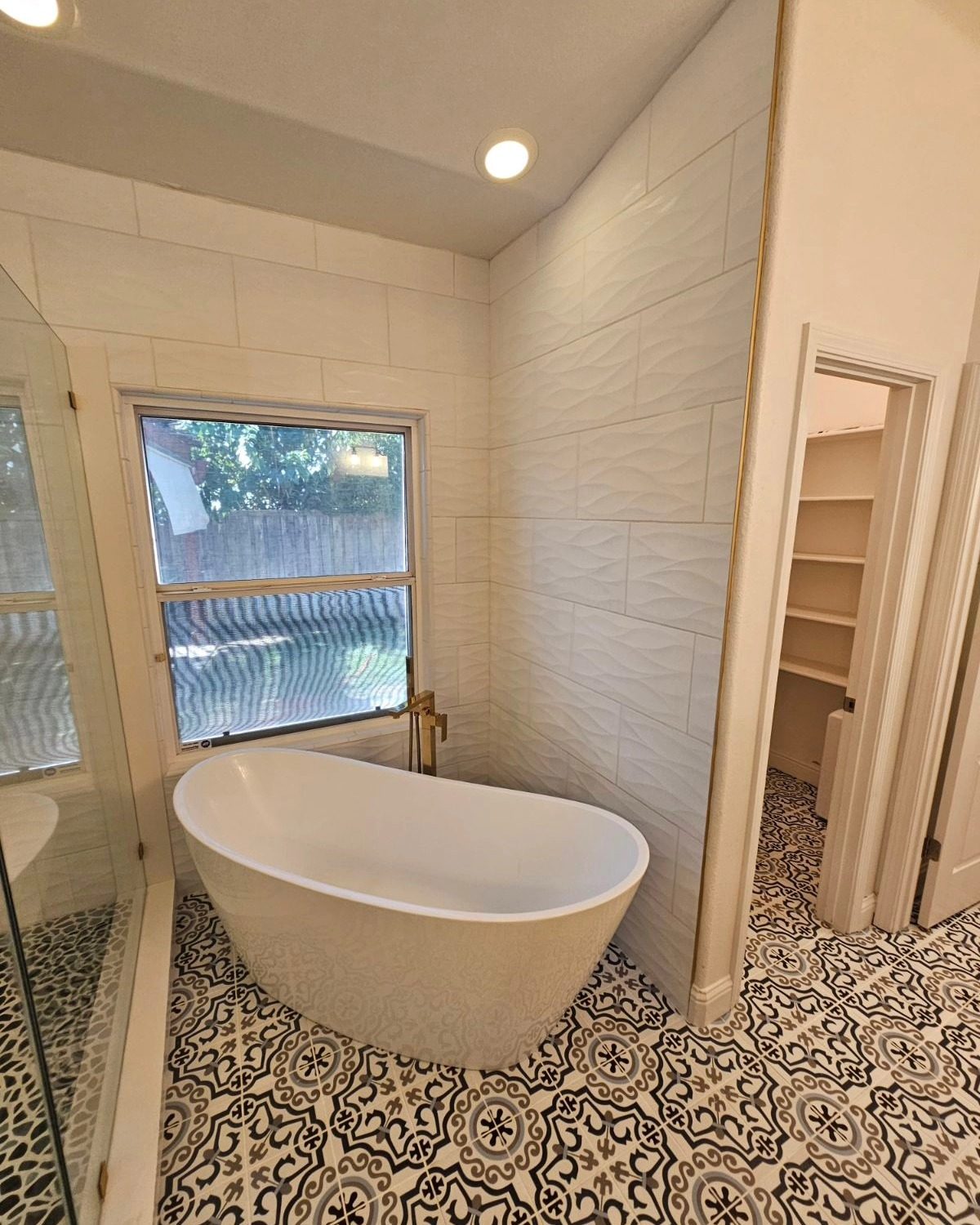 Custom bathroom remodel with freestanding soaking tub and patterned tile floor — by Palafox Prestige Construction