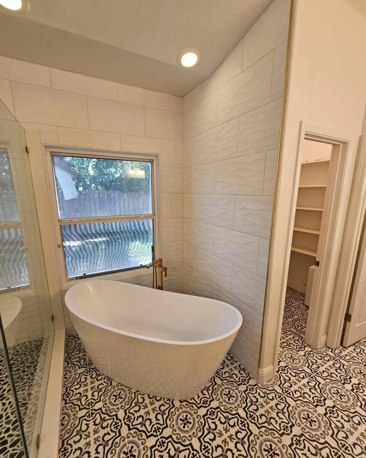Freestanding soaking tub and patterned tile in a custom bathroom remodel by Palafox Prestige Construction